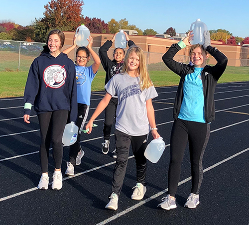 photo of girls carrying jugs of water around track 